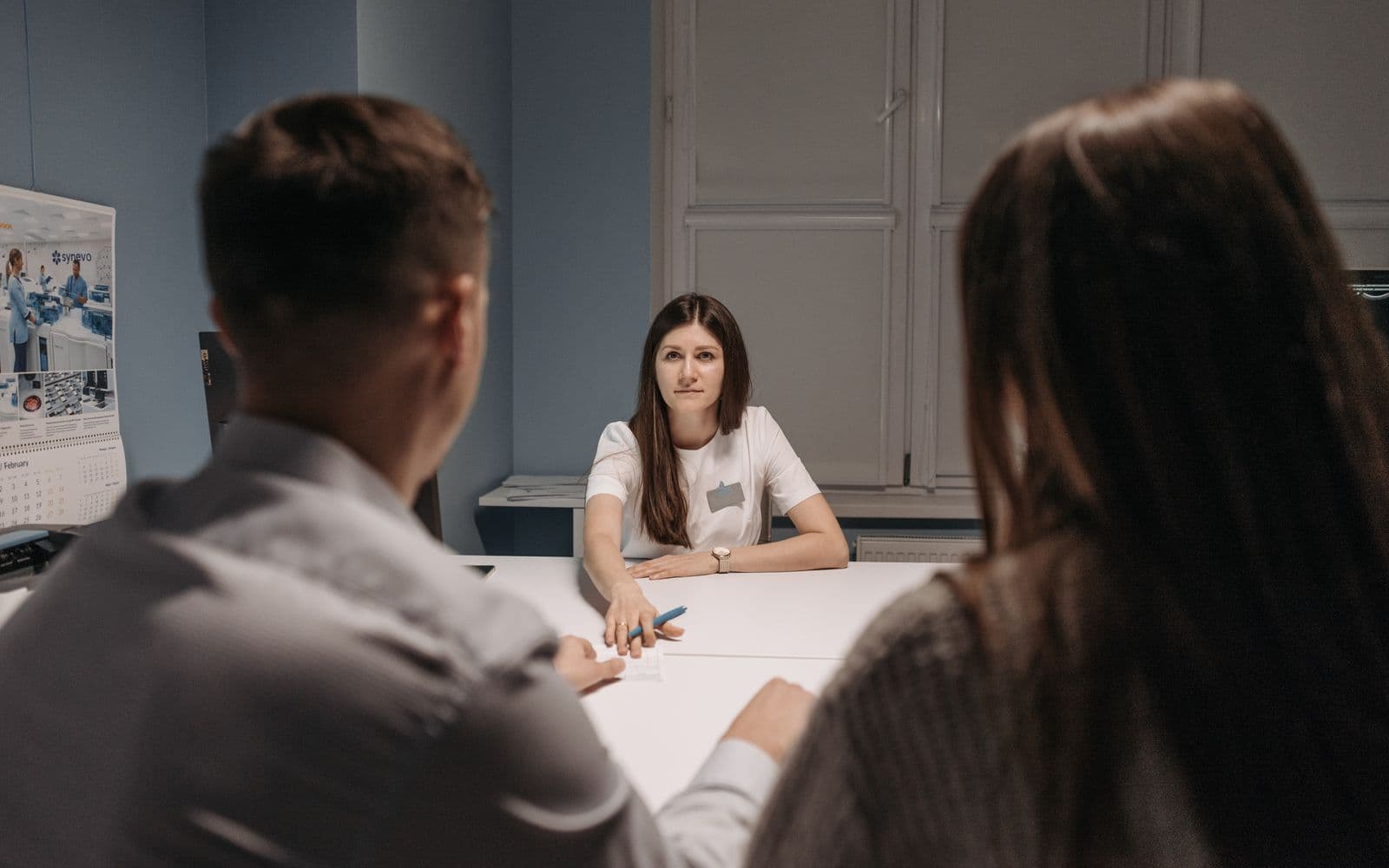 Healthcare professional meeting with two visitors at a medical office desk